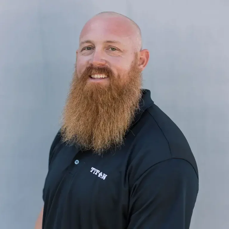 Smiling bald man with a long red beard wearing a black shirt with "TITAN" logo.