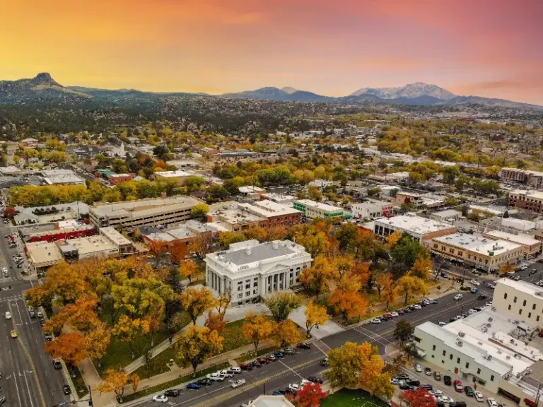 Aerial view of a town with autumn trees and a large white classical building at sunset.