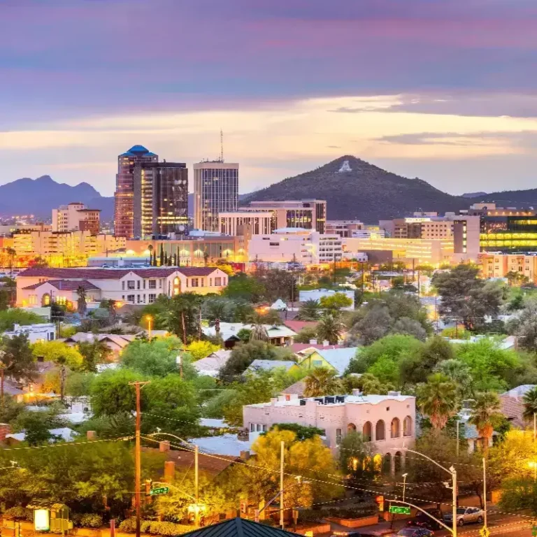 City skyline at dusk with illuminated buildings and a mountain in the background.