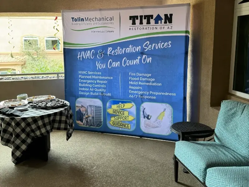 Banner displaying HVAC and restoration services with a table of snacks and a blue patterned chair nearby.